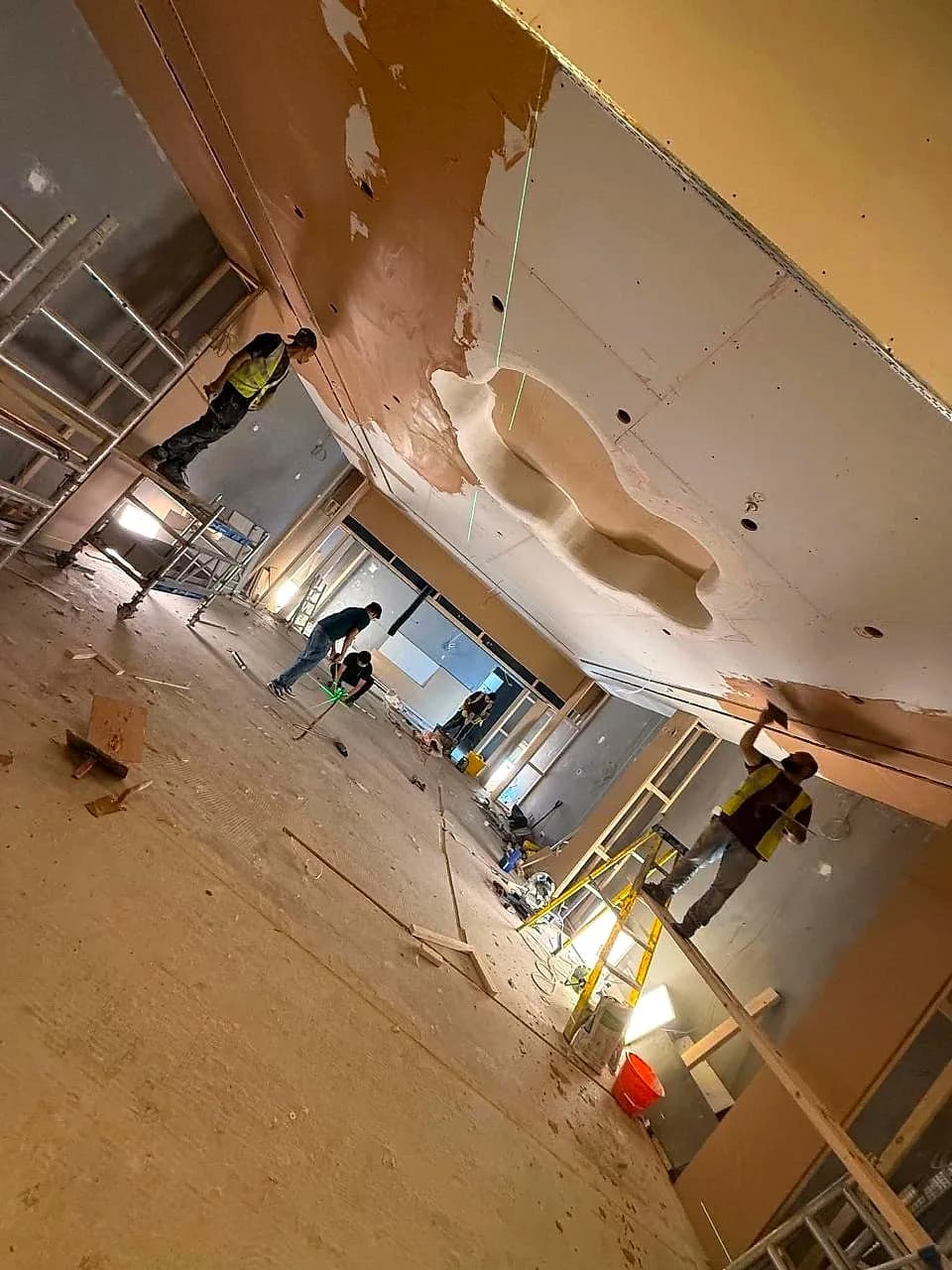 The stripped Pop Mart unit at the Trafford Centre mid-fit-out, the cloud-shaped ceiling feature being formed above a fitter in hi-vis