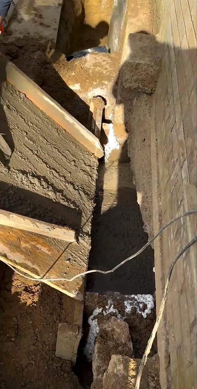 A freshly poured underpinning bay beneath the footing of a London house, shuttered in timber and propped