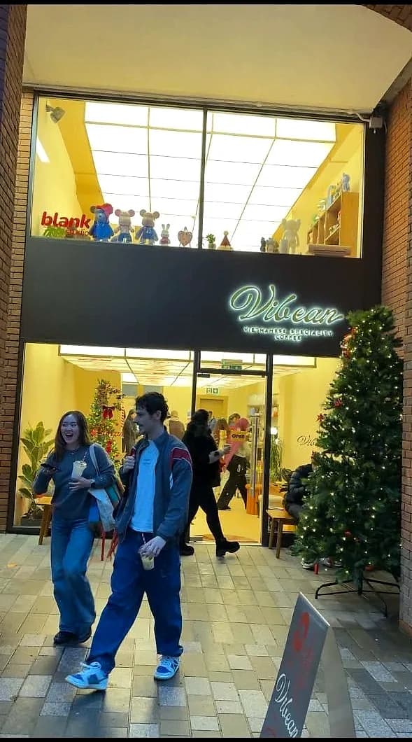 Customers walking out of the lit Vibean coffee shop doorway after opening, the fit-out complete